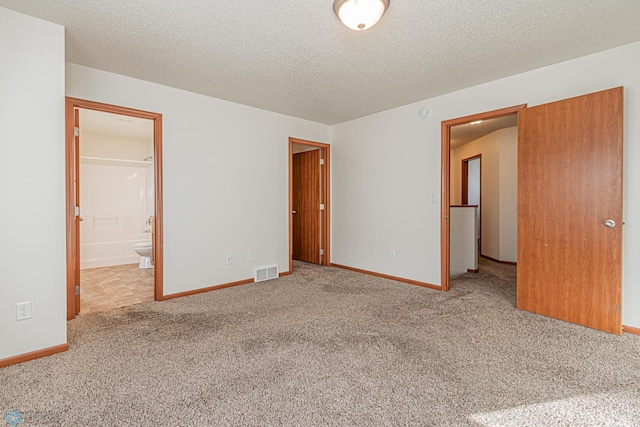 spare room featuring baseboards, visible vents, carpet floors, and a textured ceiling