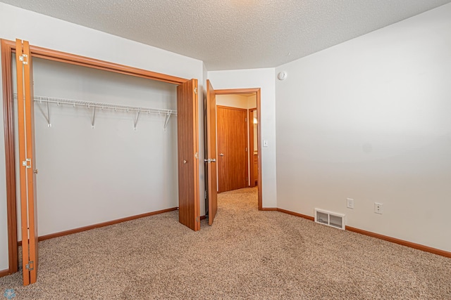 unfurnished bedroom with visible vents, baseboards, carpet, a closet, and a textured ceiling