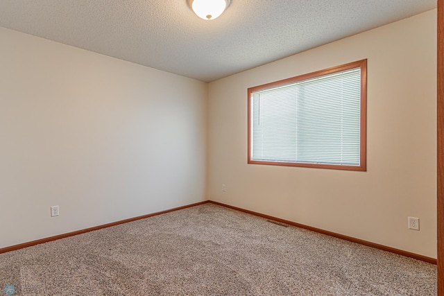 carpeted spare room featuring visible vents, a textured ceiling, and baseboards