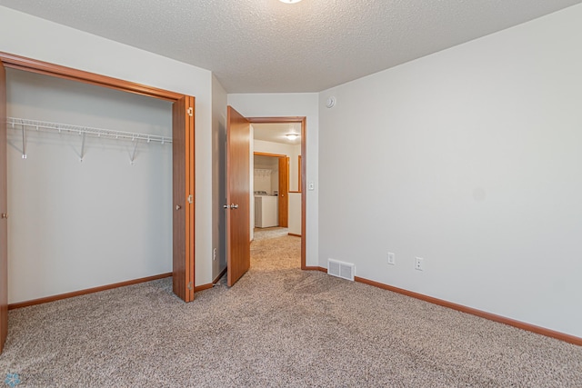 unfurnished bedroom with visible vents, a closet, carpet flooring, baseboards, and washer / dryer