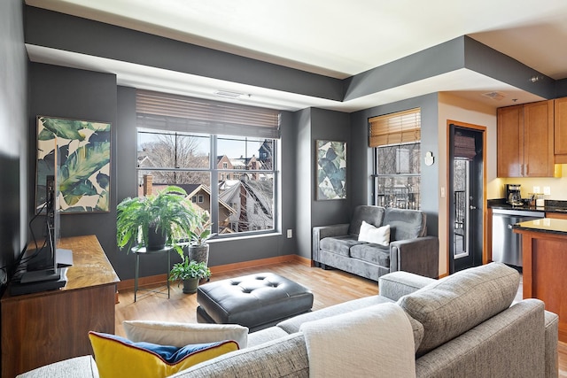 living room featuring visible vents, baseboards, and light wood-style flooring