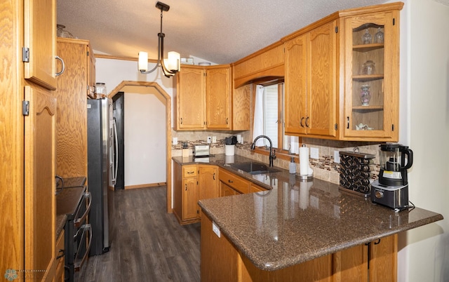 kitchen featuring double oven range, a peninsula, dark wood-style flooring, freestanding refrigerator, and a sink