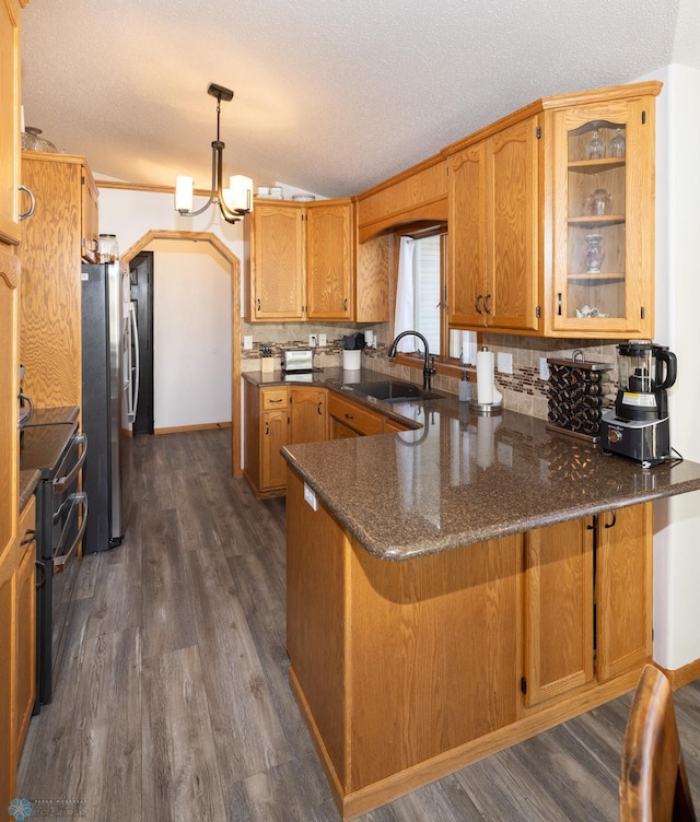 kitchen featuring dark wood-type flooring, range with two ovens, a peninsula, freestanding refrigerator, and a sink