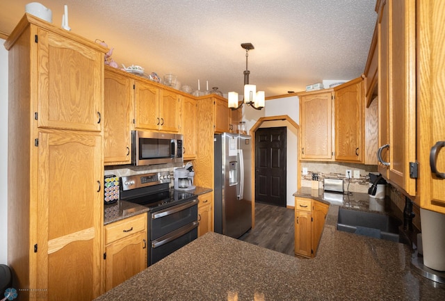 kitchen featuring a notable chandelier, a sink, tasteful backsplash, a textured ceiling, and stainless steel appliances