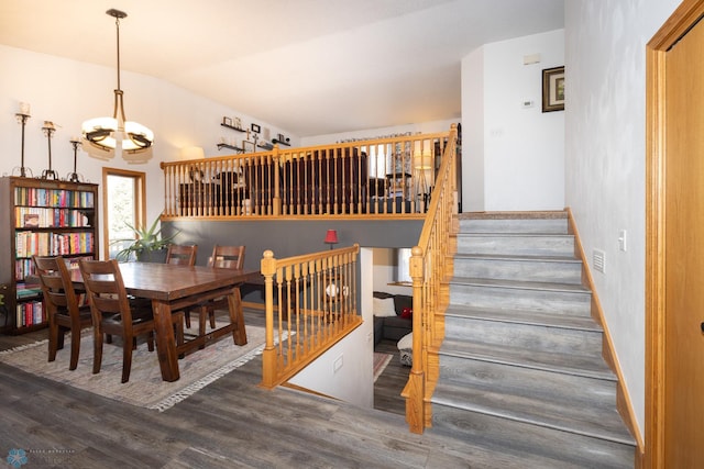 dining area with an inviting chandelier, vaulted ceiling, stairs, and wood finished floors