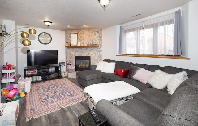 living area with a textured ceiling, a brick fireplace, and wood finished floors