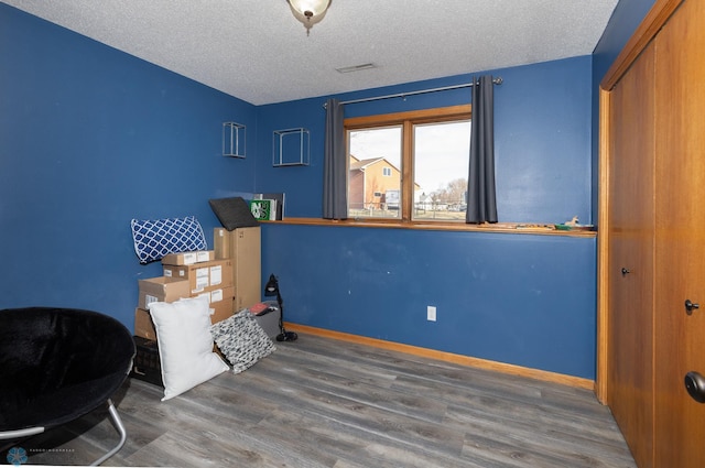 bedroom with a closet, a textured ceiling, visible vents, and wood finished floors