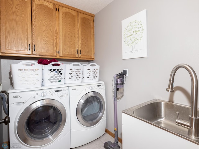 washroom with independent washer and dryer, a sink, cabinet space, light tile patterned floors, and baseboards