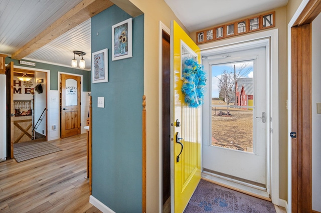 foyer entrance featuring beam ceiling, baseboards, and light wood-type flooring