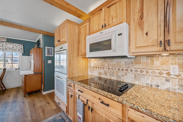 kitchen featuring white appliances, light stone counters, beam ceiling, light wood-style floors, and wainscoting