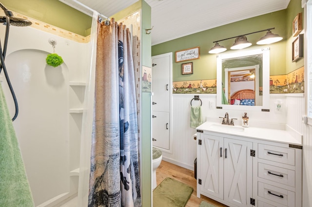 ensuite bathroom featuring vanity, ensuite bath, curtained shower, and wainscoting