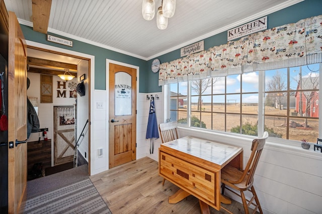 dining space featuring ornamental molding, wood finished floors, and wainscoting