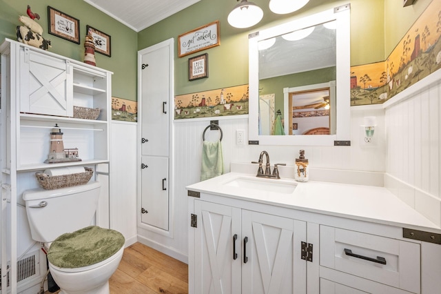 bathroom featuring vanity, wood finished floors, wainscoting, and toilet