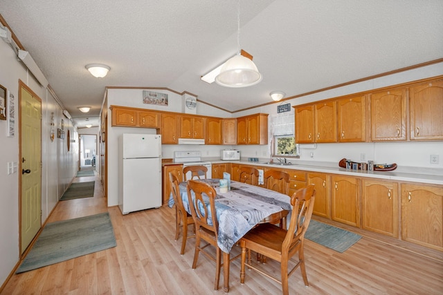 kitchen with white appliances, brown cabinetry, a sink, light countertops, and vaulted ceiling