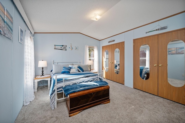 carpeted bedroom with two closets, a textured ceiling, french doors, crown molding, and vaulted ceiling