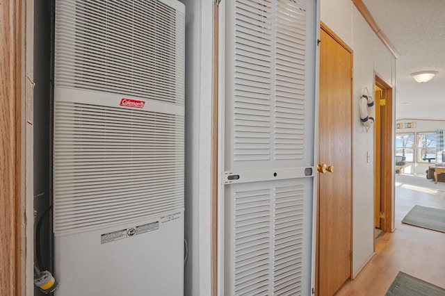 interior details with a textured ceiling, a heating unit, and wood finished floors