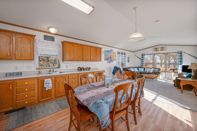 dining space with visible vents, light wood-style flooring, ornamental molding, vaulted ceiling, and a textured ceiling