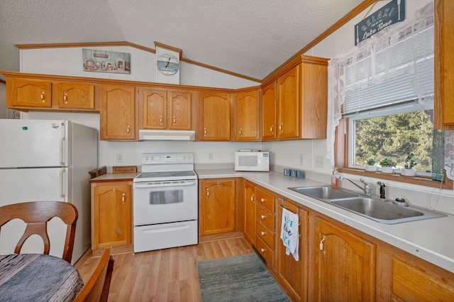 kitchen with a sink, under cabinet range hood, a textured ceiling, white appliances, and lofted ceiling