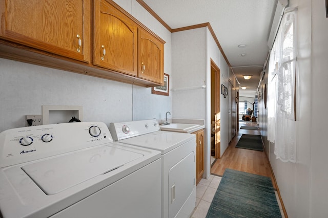 laundry area with ornamental molding, a sink, cabinet space, light tile patterned floors, and washing machine and clothes dryer