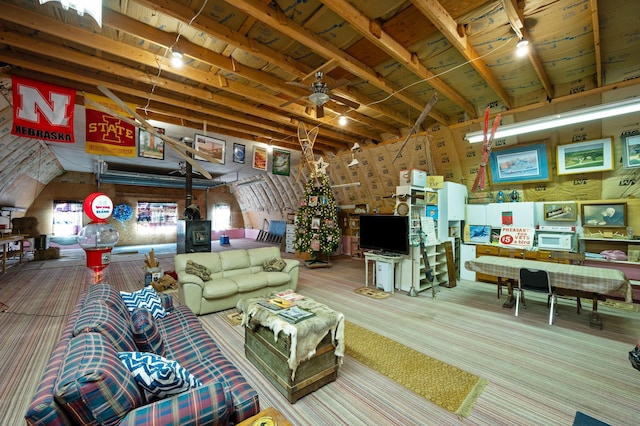 carpeted living room featuring a wood stove and a ceiling fan