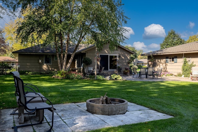 rear view of property with a yard, a patio area, and an outdoor fire pit