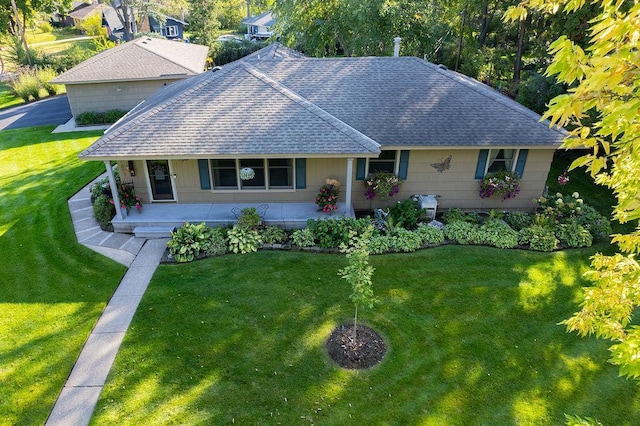 view of front of home featuring covered porch, roof with shingles, and a front yard