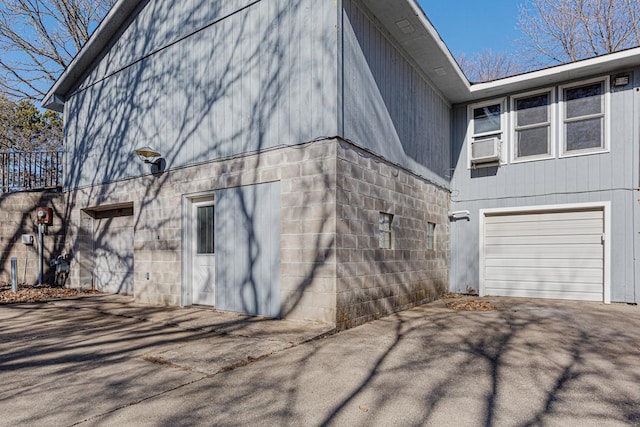 view of property exterior featuring aphalt driveway, cooling unit, and an attached garage