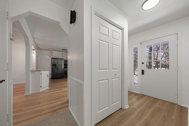 hallway with light wood-type flooring and a textured ceiling