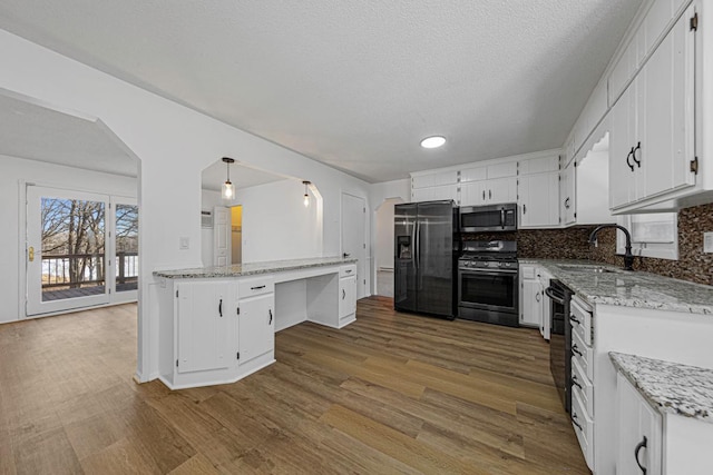 kitchen featuring a sink, appliances with stainless steel finishes, wood finished floors, and white cabinetry