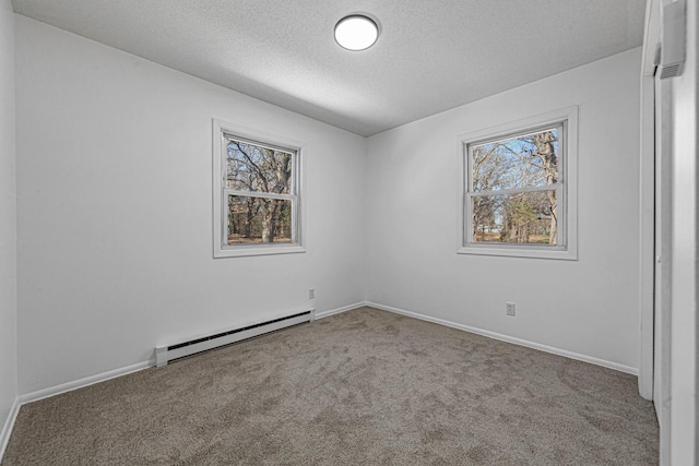 carpeted empty room with a textured ceiling, a baseboard heating unit, and baseboards