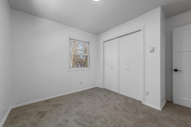 unfurnished bedroom featuring baseboards, a closet, carpet floors, and a textured ceiling