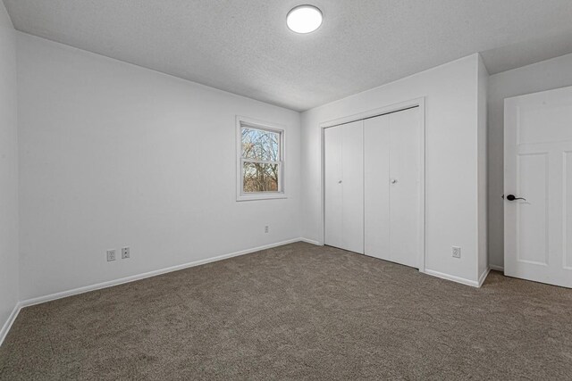 unfurnished bedroom featuring a closet, carpet floors, a textured ceiling, and baseboards