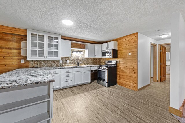 kitchen featuring white cabinets, appliances with stainless steel finishes, light wood-type flooring, and a sink