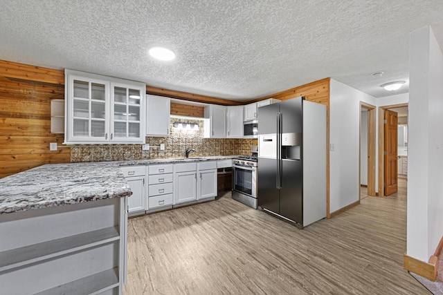 kitchen with white cabinets, appliances with stainless steel finishes, light wood-type flooring, and a sink