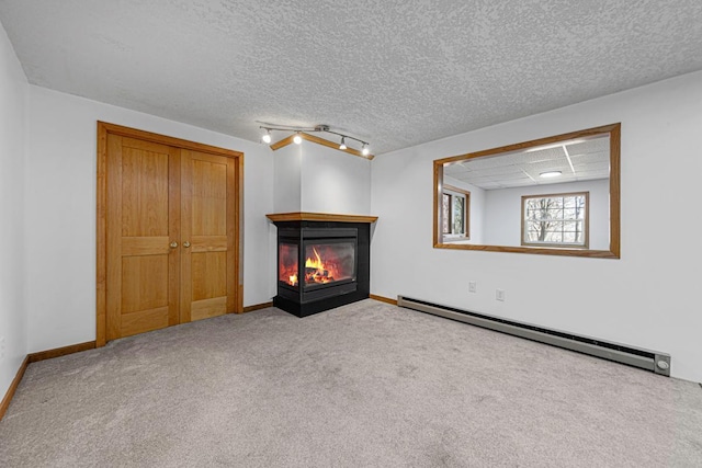 unfurnished bedroom featuring a multi sided fireplace, baseboard heating, carpet flooring, and baseboards