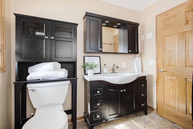 bathroom featuring baseboards, toilet, and vanity