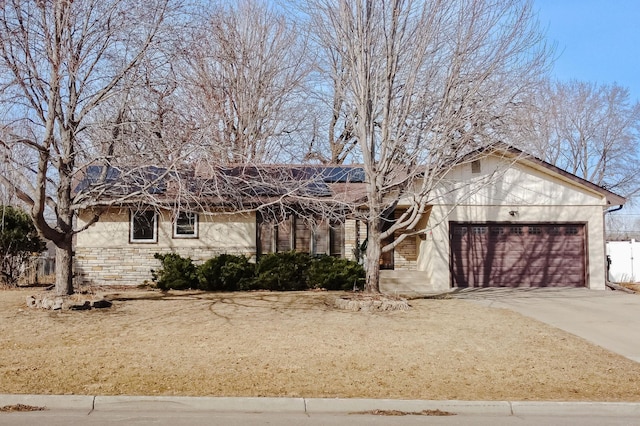 single story home featuring stone siding, roof mounted solar panels, concrete driveway, and an attached garage