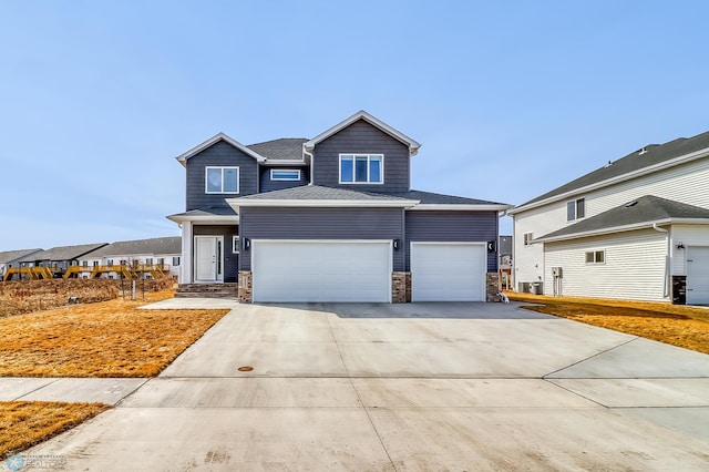 craftsman-style home featuring concrete driveway, an attached garage, and a shingled roof