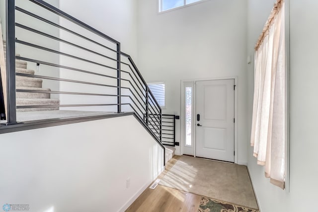 entryway featuring stairs, wood finished floors, and a towering ceiling