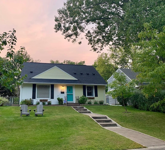 view of front of property featuring a front lawn, fence, and a shingled roof