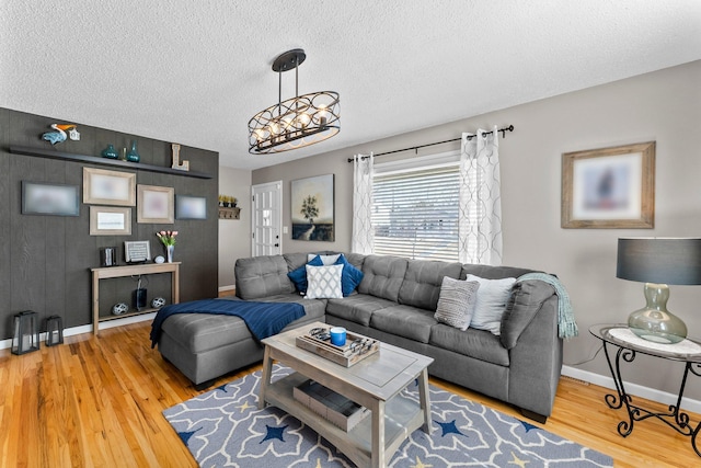 living area with wood finished floors, baseboards, a chandelier, and a textured ceiling