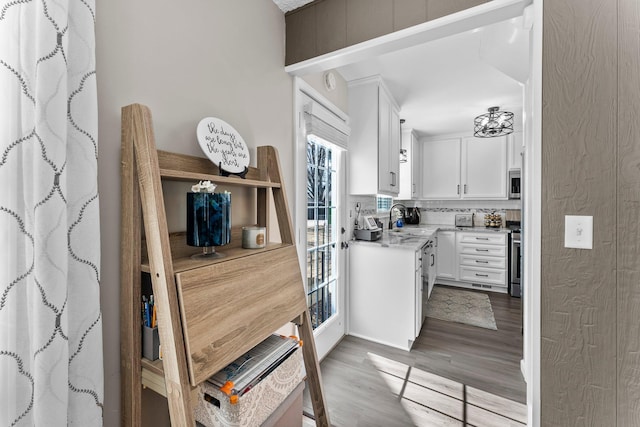 kitchen featuring a sink, white cabinets, light wood-style floors, appliances with stainless steel finishes, and tasteful backsplash