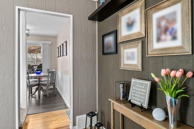 corridor featuring visible vents, a textured ceiling, and wood finished floors