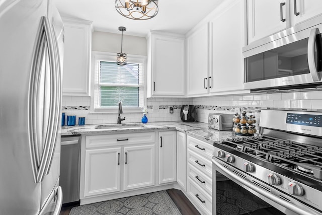 kitchen with a sink, backsplash, appliances with stainless steel finishes, and white cabinets