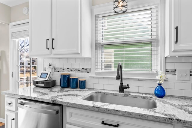 kitchen with light stone countertops, white cabinetry, a sink, decorative backsplash, and dishwasher