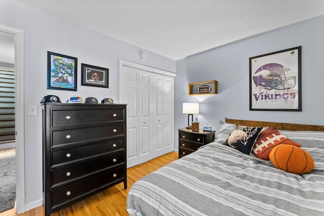 bedroom with baseboards, wood finished floors, a closet, and a textured ceiling