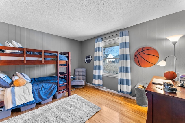 bedroom featuring wood finished floors, baseboards, and a textured ceiling