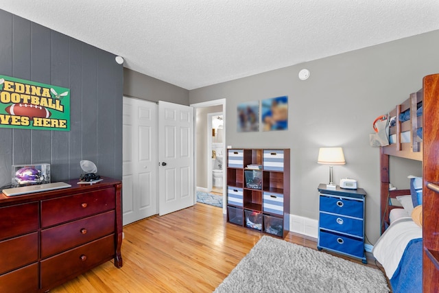 bedroom featuring a closet, baseboards, a textured ceiling, and wood finished floors