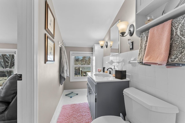 bathroom featuring tile walls, tile patterned flooring, toilet, and vanity