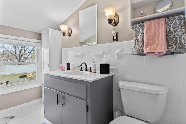 bathroom with tile walls, toilet, and vanity